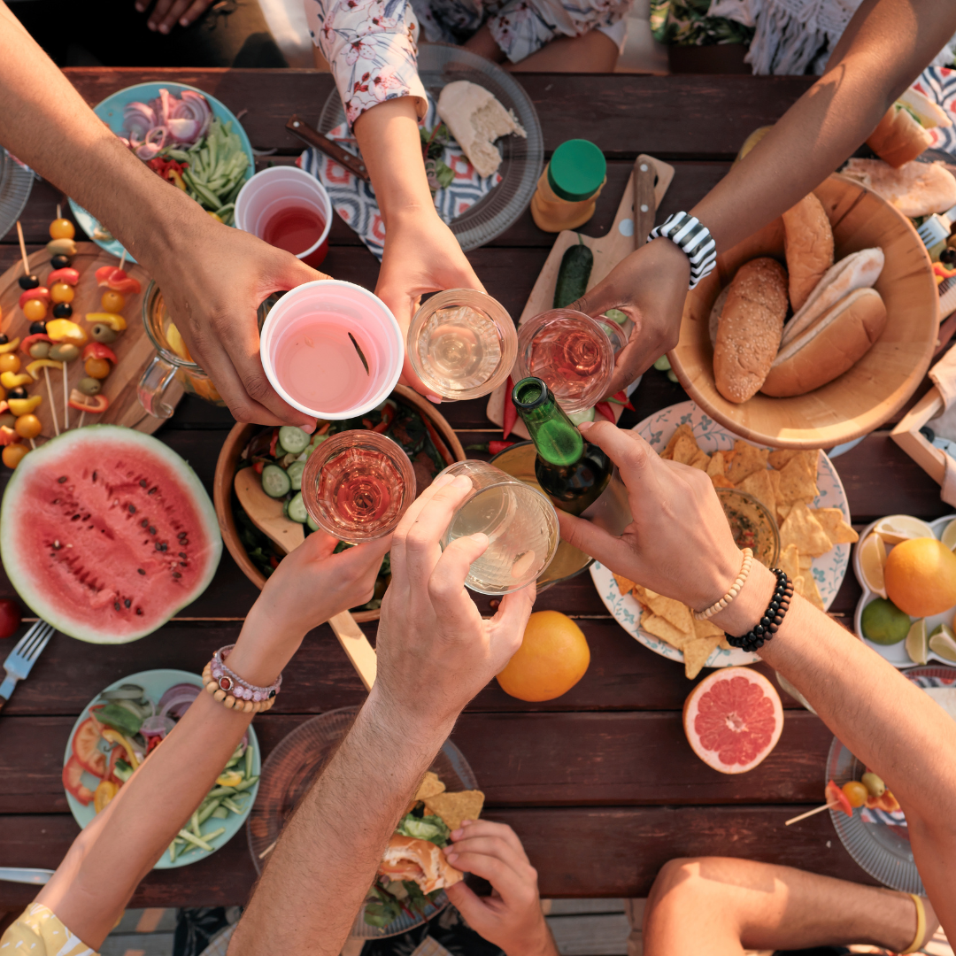 Ein Tisch mit Essen, über dem sechs Personen mit Getränken anstoßen