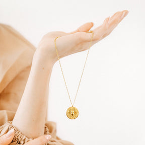 Halskette von bee graced in gold in der Hand gehalten